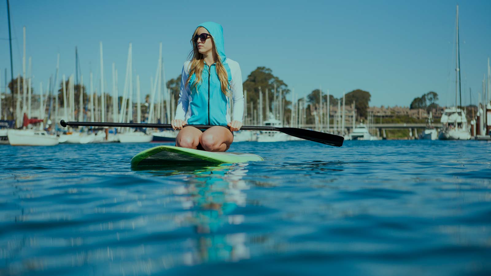 Girl paddle boarding trough the cristal clear water. Stand Up Paddle boarding - SUP Apparel.