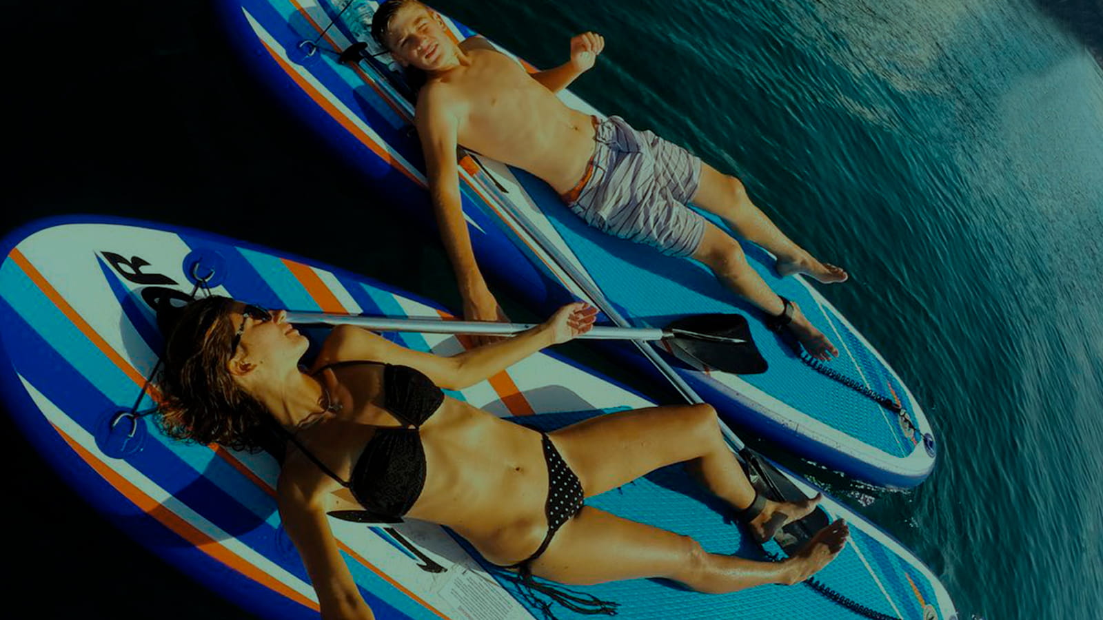 Haapy couple sunbathing on a Stand up Paddle boards. Sup Boards. Warm weather pleasure.