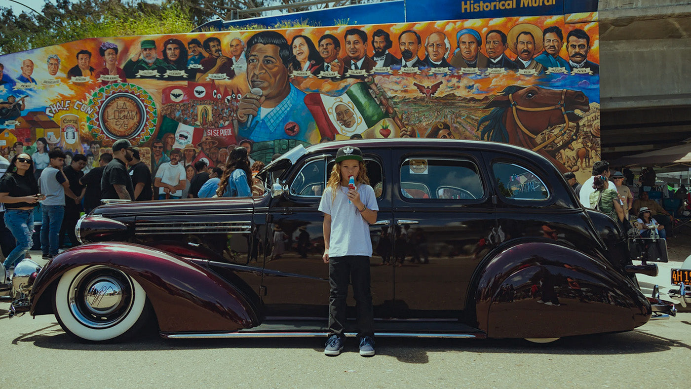 Lifestyle. Surfer kid standing in front of a hot-rod lowrider car.