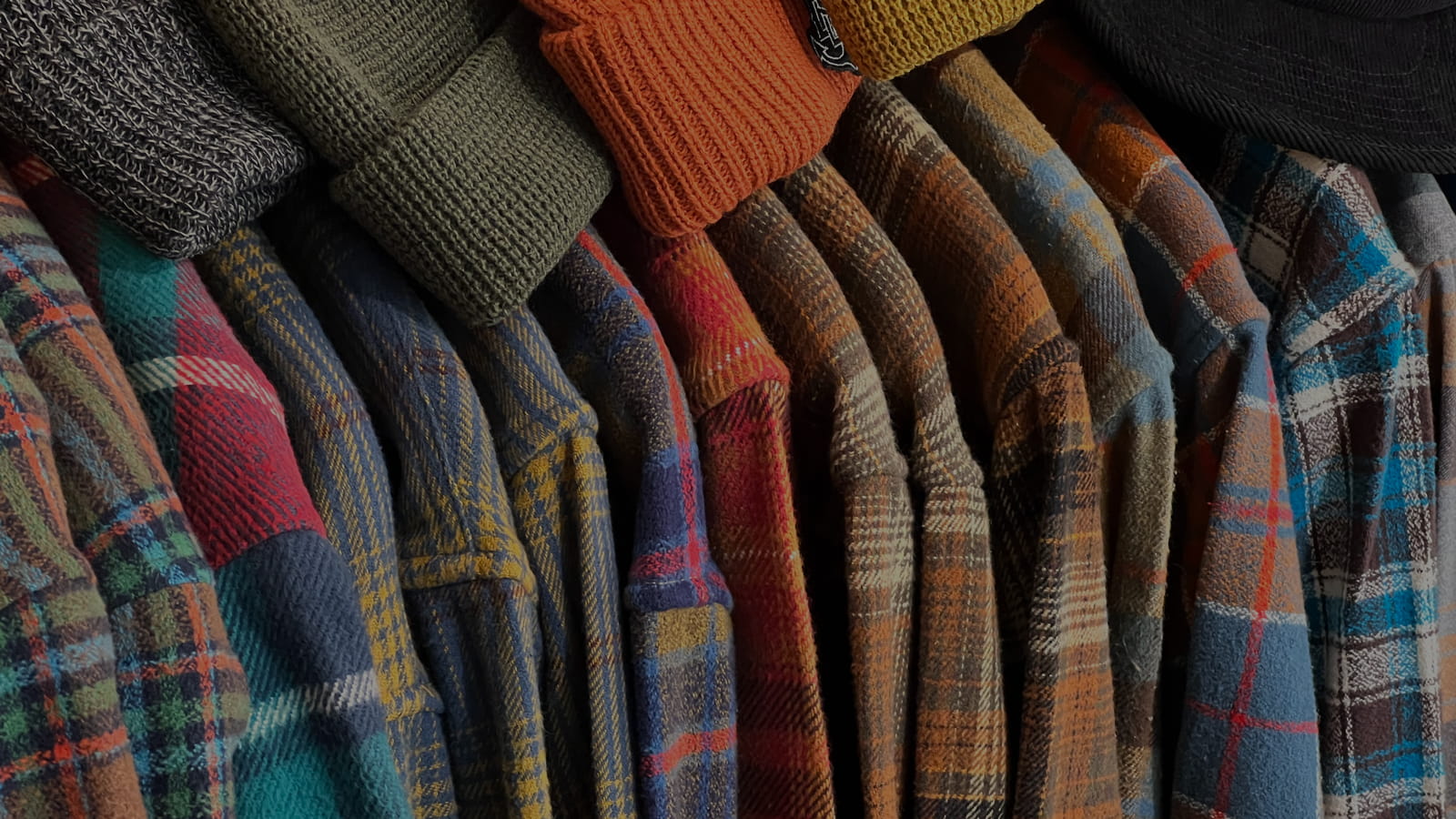 Stack of various flannel shirts and beanies.