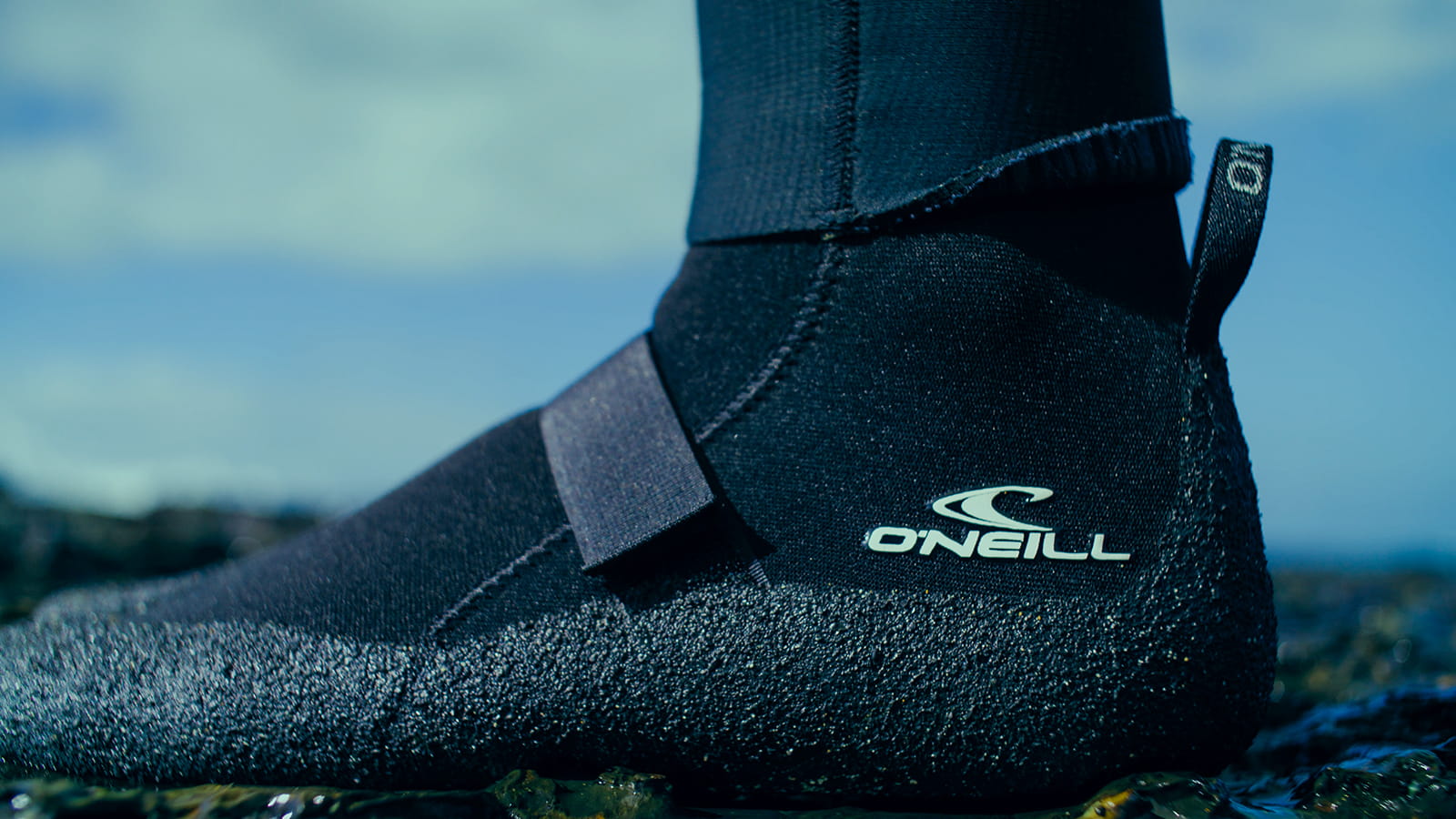 Neoprene boots. Rubber outsole. Rocky buttom. Blue nature background.