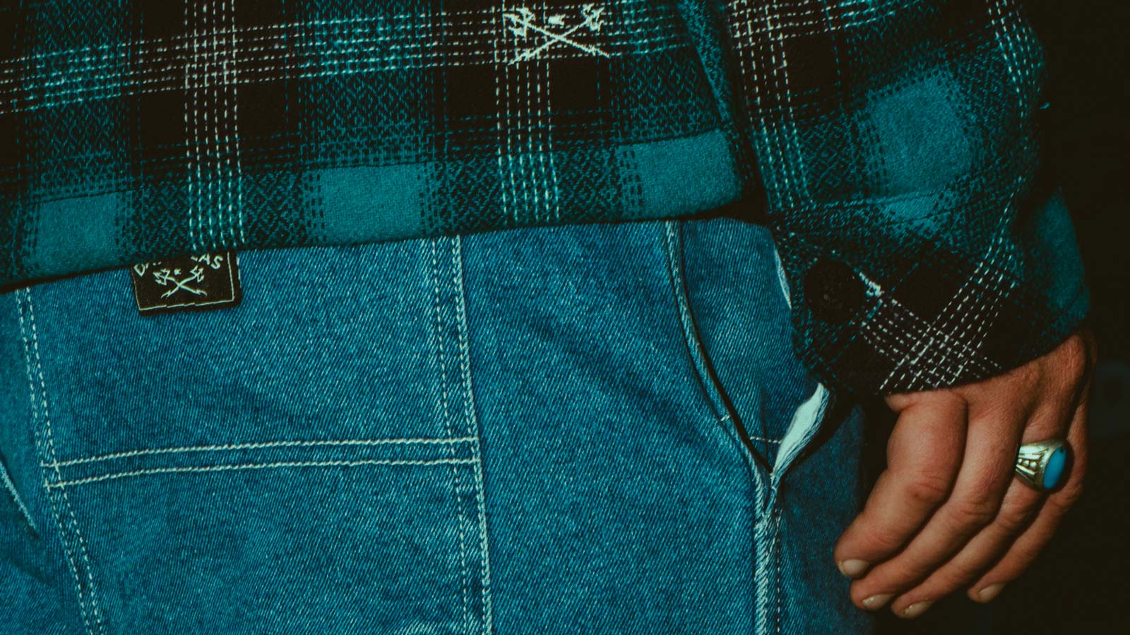 Casual denim pants. Flannel Shirt. Hand with a ring.
