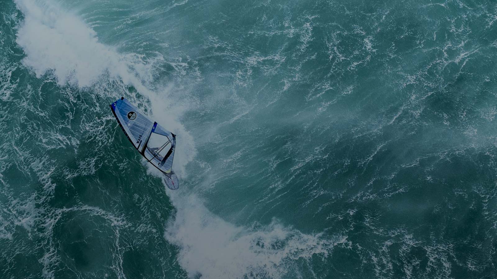 Windsurfer catching a wave in a windy and rough sea.